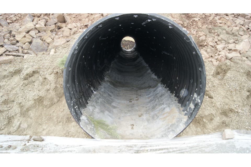 Водопропускная гофрированная труба с бетонным лотком на дне для защиты от абразивных веществ, находящихся в воде